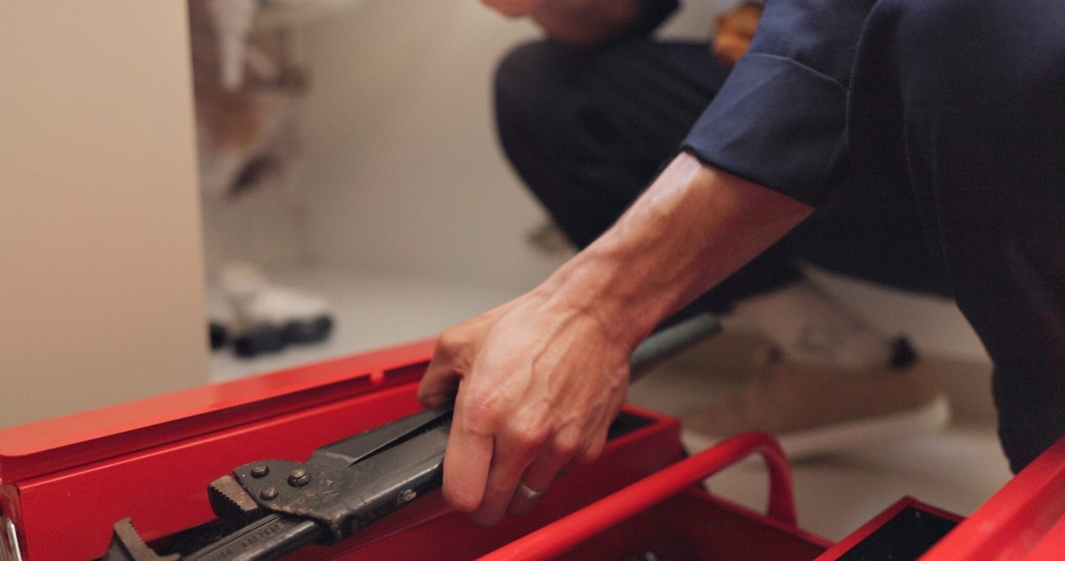 Technician Selecting Wrench from Toolbox for Plumbing Services
