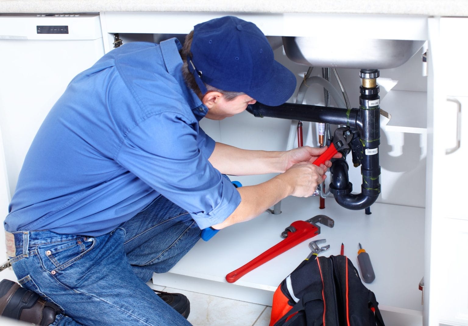 Plumber Fixing Kitchen Sink Pipe with Wrench
