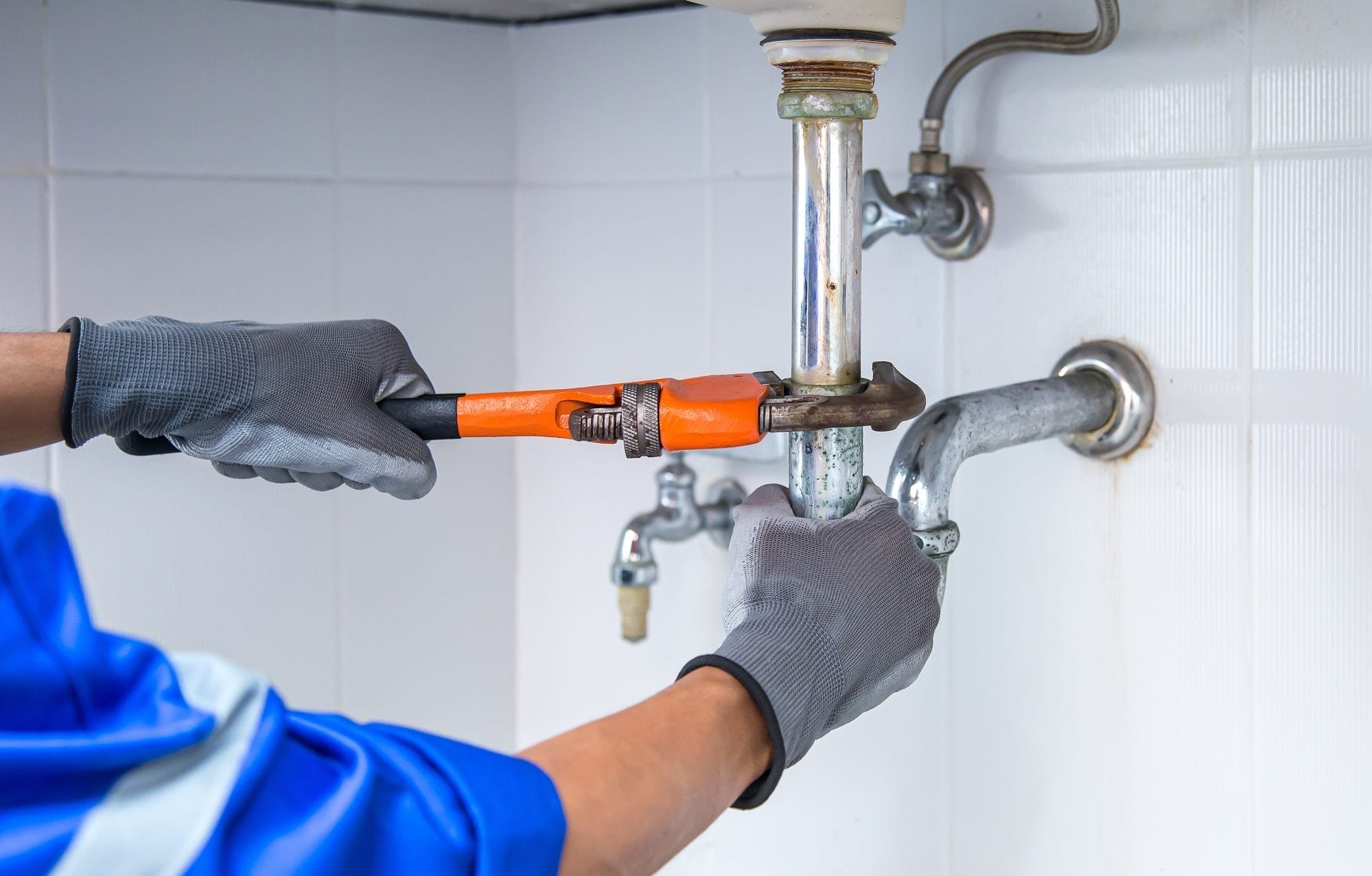 Plumber tightening pipe connection under sink during installation
