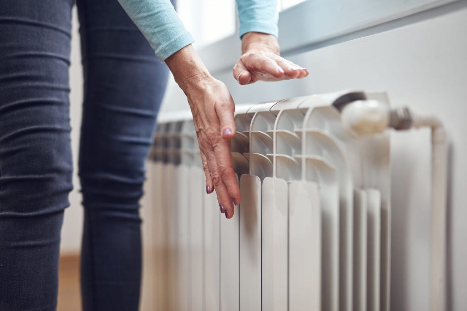 Person Inspecting Home Heater Radiator
